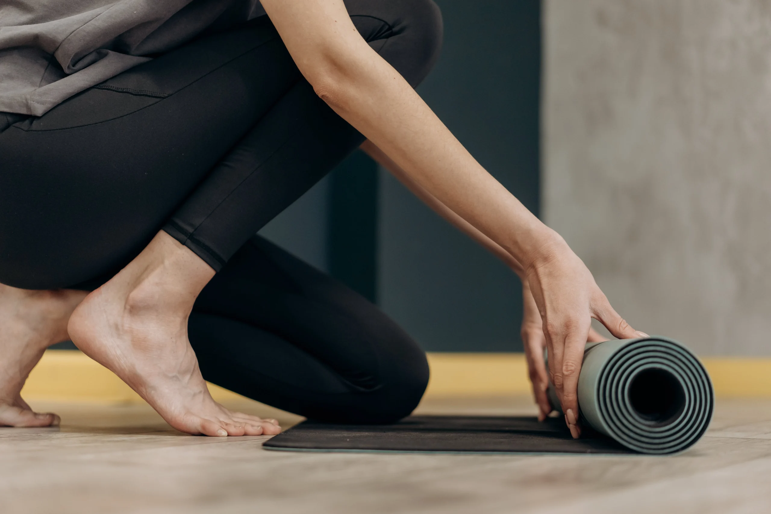 a woman rolls out a black yoga mat